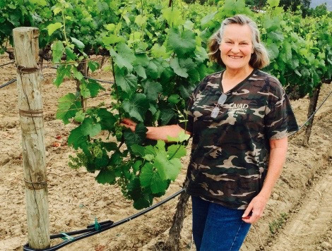 Alison Green-Doran stands by grape vines